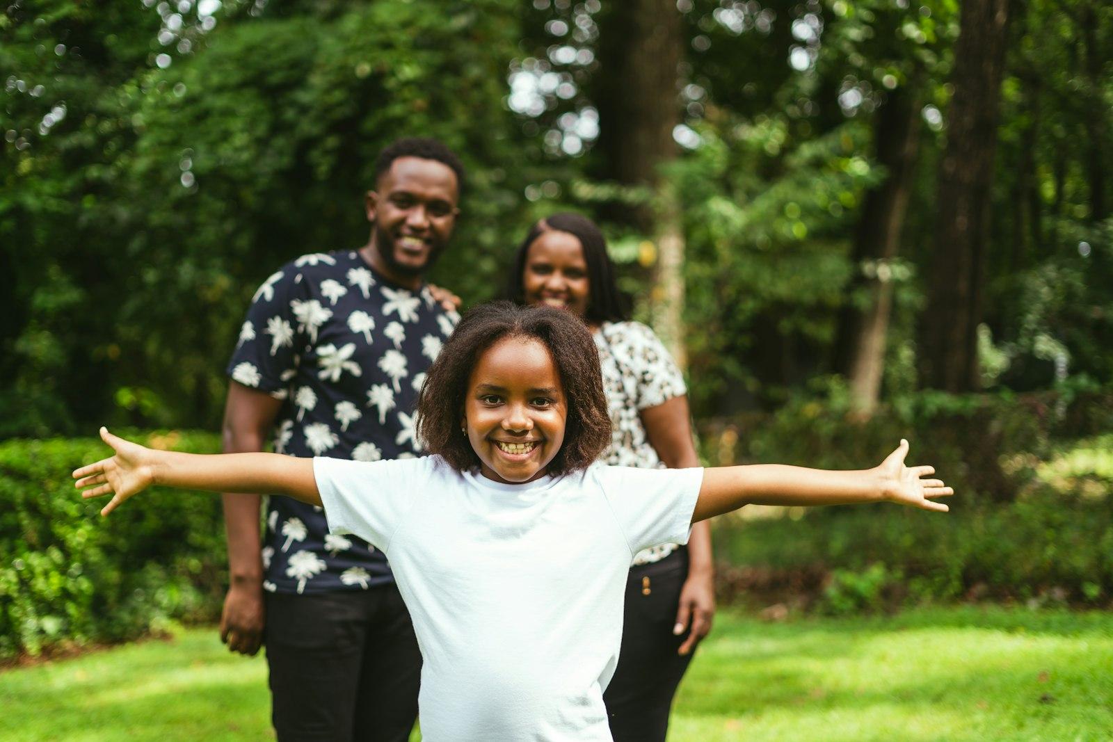 A father, mother, and their daughter laughing together outdoors